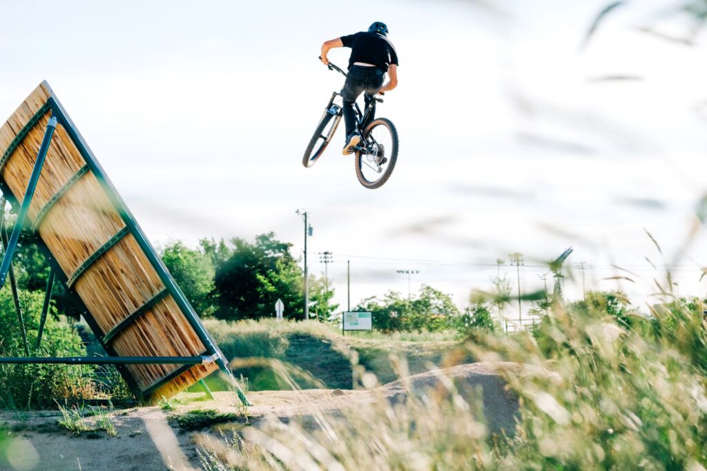 Mountain biker getting big air with his bike off a dirt berm jump at Boise Bike Park in Boise, Idaho.