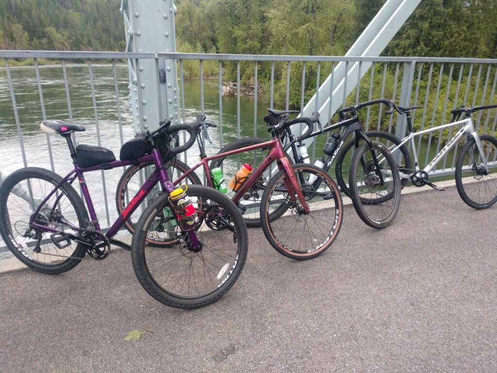 Four bikes standing and leaning against the railing of a bridge over a lake.  