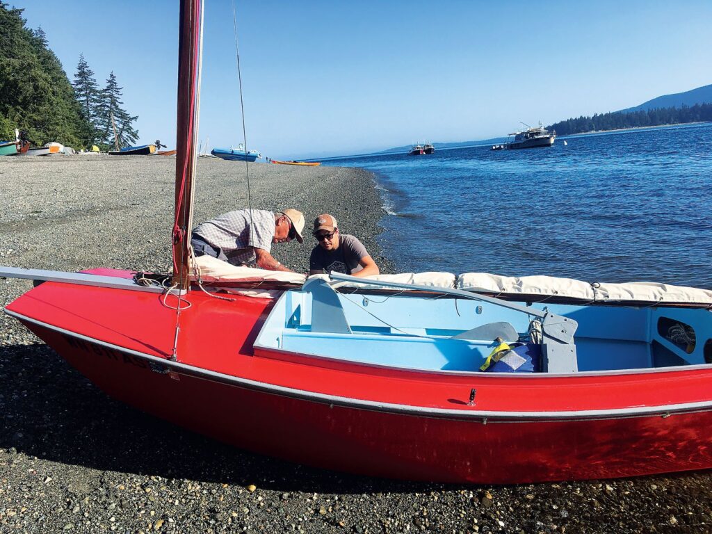 Author and boatbuilder examining Chris's sailboat while it rests on a rocky beach.