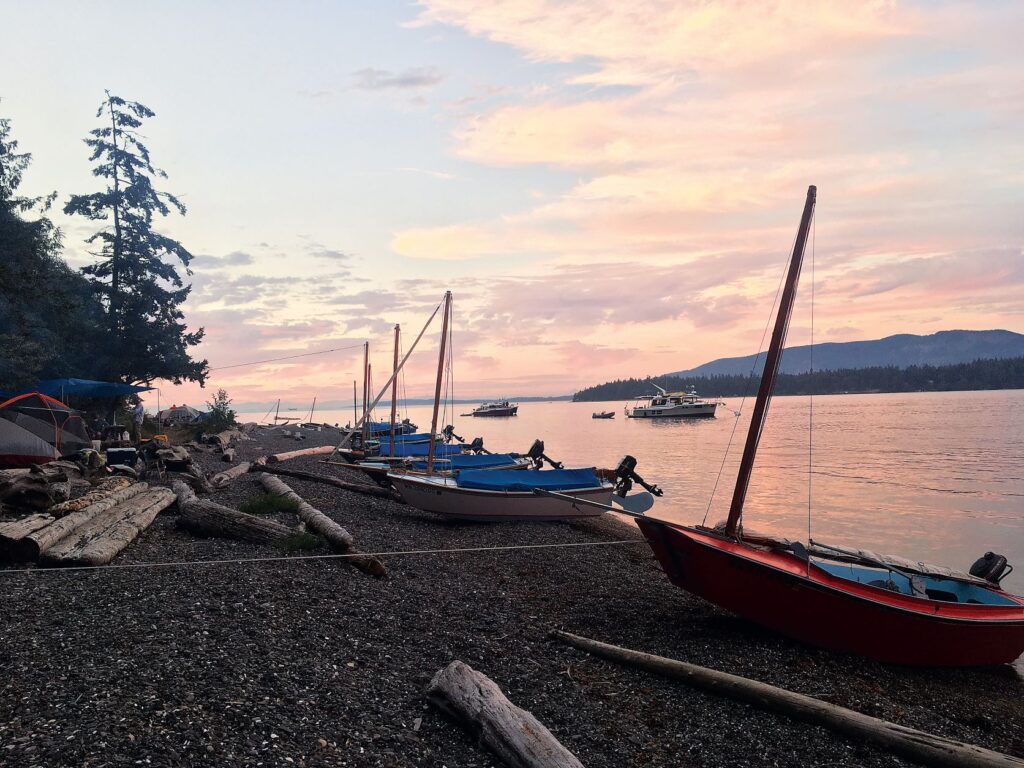 Pelican Sailboats resting on the rocky Pelican Beach at sunset.