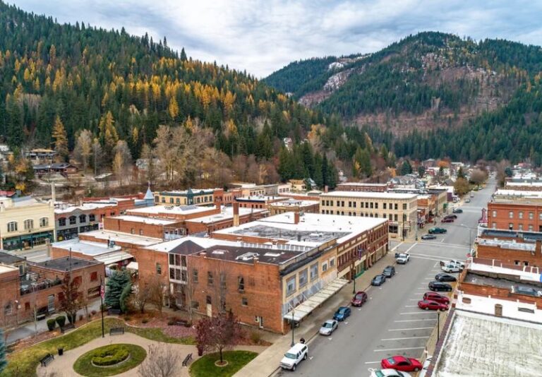 Aerial view of downtown Wallace, Idaho, featuring historic red-brick buildings in the downtown business area, surrounded by forested hills.