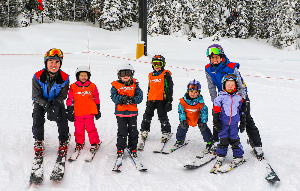 Young skiers and their instructor smiling for the camera.