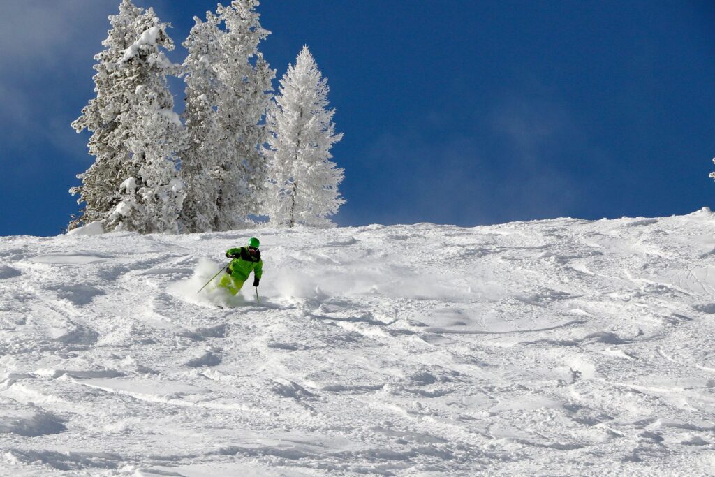 Skier making turns with spraying snow on a powder day at Lookout Pass.
