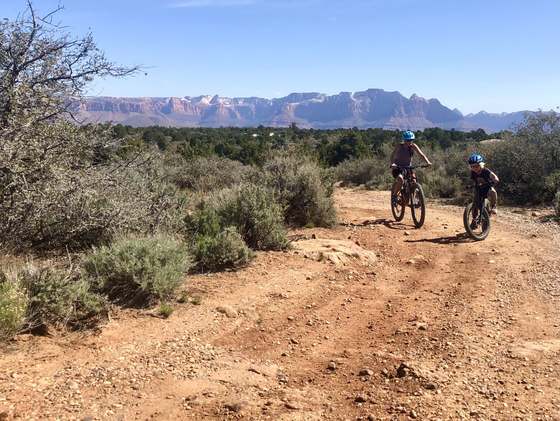 Mother and son mountain bike on a trail in the desert.